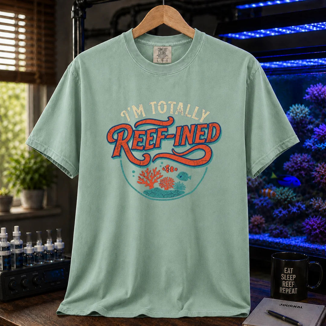 Saltwater aquarium graphic t-shirt design featuring distressed typography reading I'm Totally Reef-Ined with a circular coral and fish scene on a light green tee