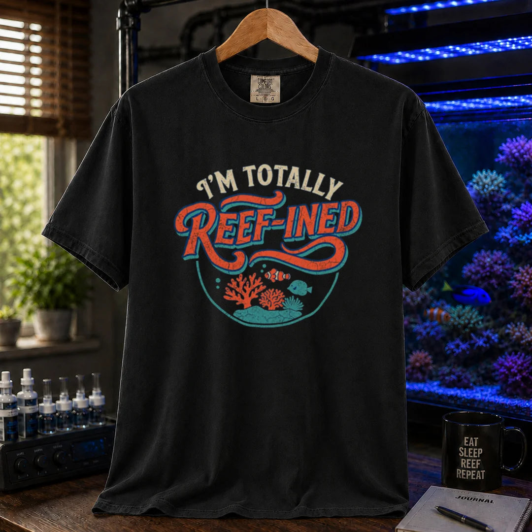 Saltwater aquarium graphic t-shirt design featuring distressed typography reading I'm Totally Reef-Ined with a circular coral and fish scene on a black tee
