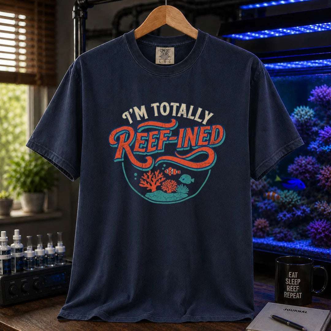 Saltwater aquarium graphic t-shirt design featuring distressed typography reading I'm Totally Reef-Ined with a circular coral and fish scene on a NAVY tee
