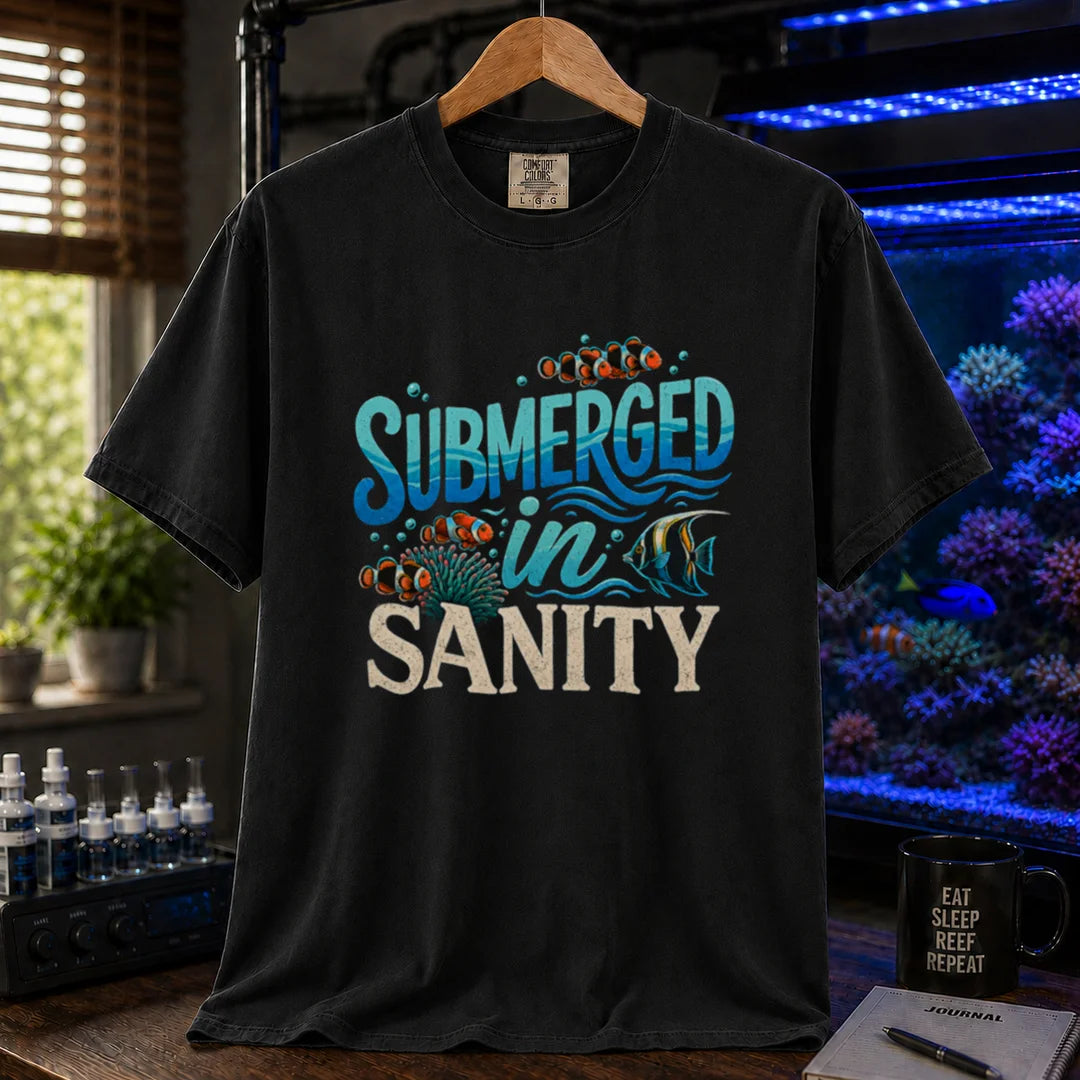 Saltwater aquarium graphic t-shirt design featuring wavy blue typography reading Submerged In Sanity with clownfish and coral artwork on a BLACK tee