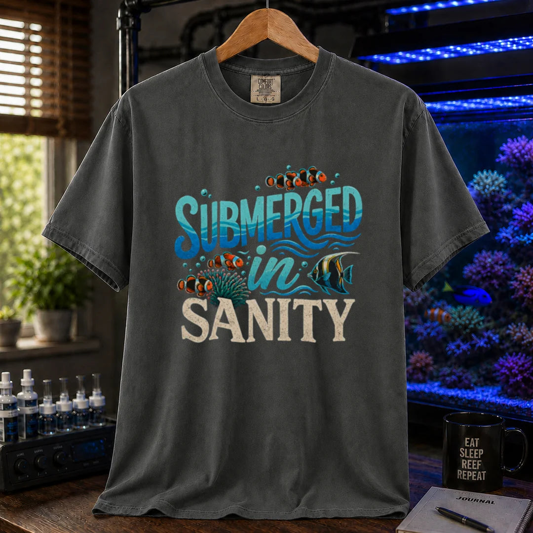Saltwater aquarium graphic t-shirt design featuring wavy blue typography reading Submerged In Sanity with clownfish and coral artwork on a dark grey tee