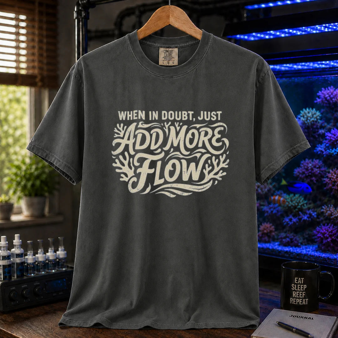 Saltwater aquarium graphic t-shirt featuring distressed cream typography reading When In Doubt, Just Add More Flow with coral accents printed on a dark grey tee displayed in a reef room setting