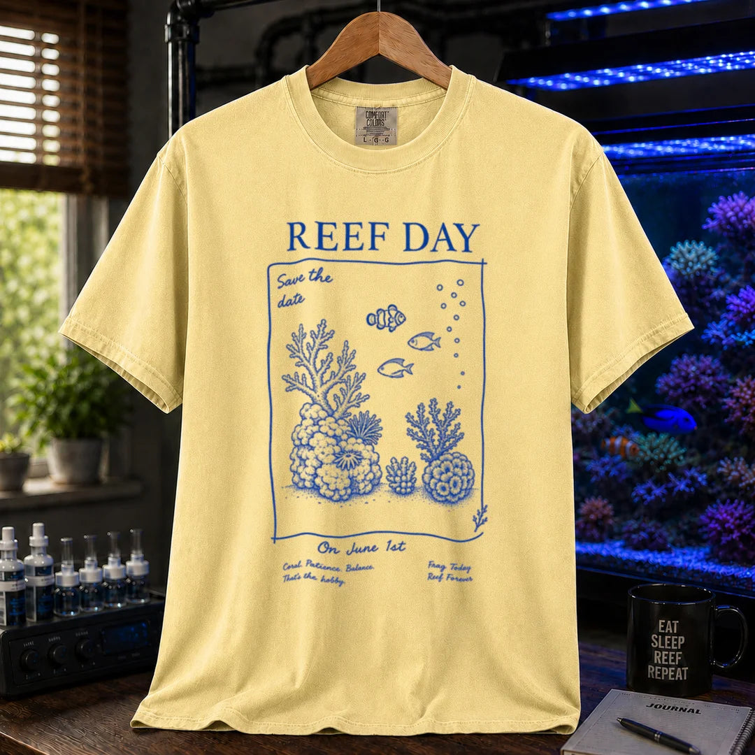 Saltwater aquarium graphic t-shirt featuring blue line-art typography and illustrations reading Reef Day Save The Date On June 1st with coral and fish graphics printed on a yellow tee displayed in a reef room setting