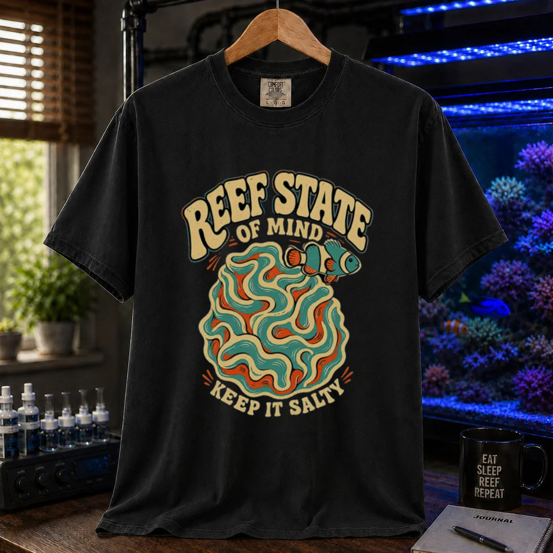Saltwater aquarium graphic t-shirt featuring retro cream typography reading Reef State Of Mind Keep It Salty with a swirling abstract coral and clownfish design printed on a black tee displayed in a reef room setting