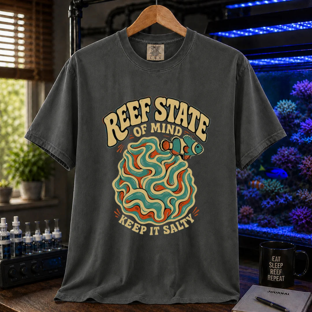 Saltwater aquarium graphic t-shirt featuring retro cream typography reading Reef State Of Mind Keep It Salty with a swirling abstract coral and clownfish design printed on a dark grey tee displayed in a reef room setting