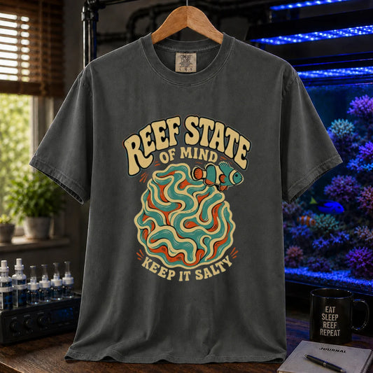 Saltwater aquarium graphic t-shirt featuring retro cream typography reading Reef State Of Mind Keep It Salty with a swirling abstract coral and clownfish design printed on a dark grey tee displayed in a reef room setting