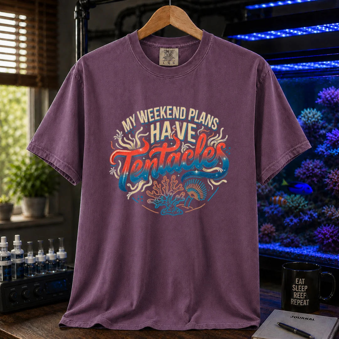 Saltwater aquarium graphic t-shirt featuring distressed cream, turquoise, and red gradient typography reading My Weekend Plans Have Tentacles with coral and polyp graphics printed on a purple tee displayed in a reef room setting