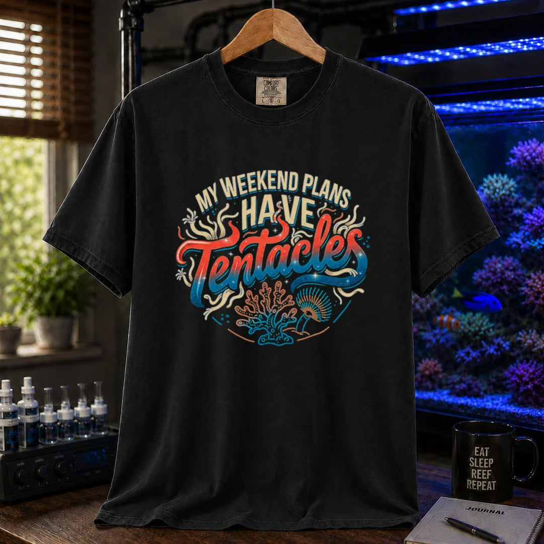 Saltwater aquarium graphic t-shirt featuring distressed cream, turquoise, and red gradient typography reading My Weekend Plans Have Tentacles with coral and polyp graphics printed on a black tee displayed in a reef room setting
