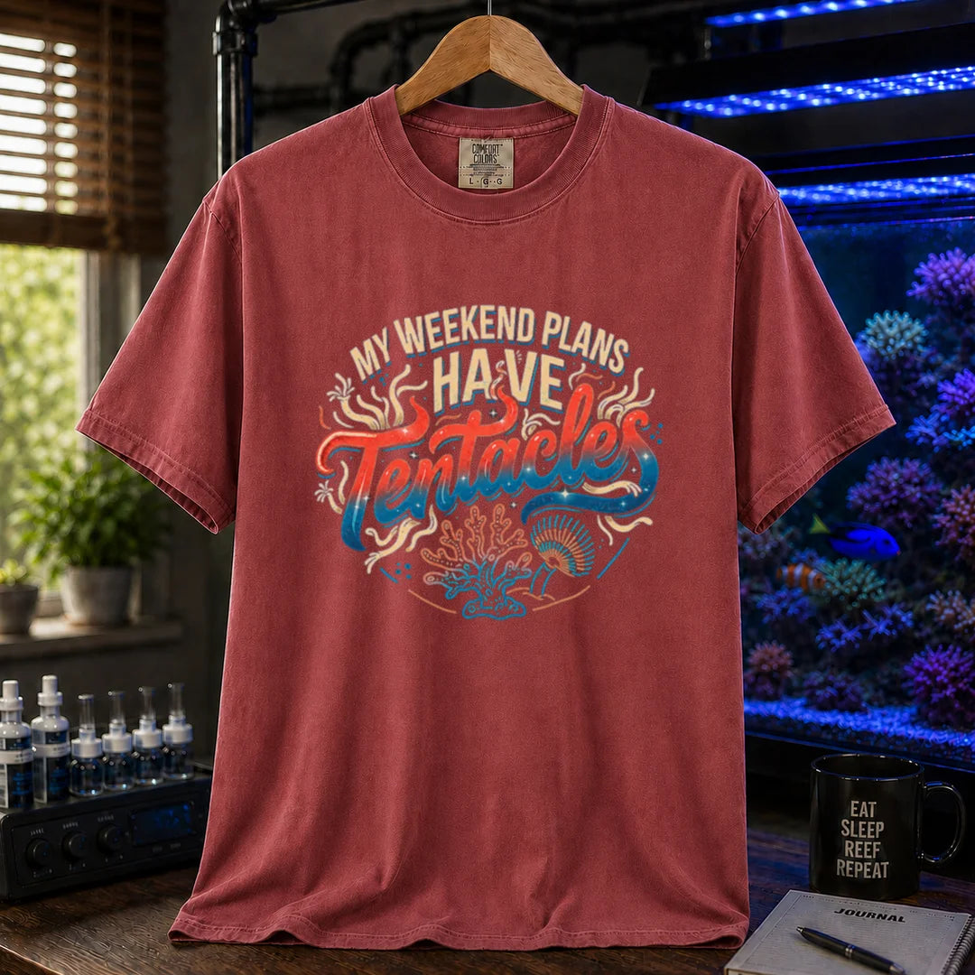 Saltwater aquarium graphic t-shirt featuring distressed cream, turquoise, and red gradient typography reading My Weekend Plans Have Tentacles with coral and polyp graphics printed on a maroon, red tee displayed in a reef room setting