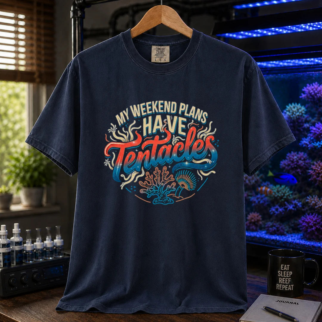 Saltwater aquarium graphic t-shirt featuring distressed cream, turquoise, and red gradient typography reading My Weekend Plans Have Tentacles with coral and polyp graphics printed on a navy tee displayed in a reef room setting