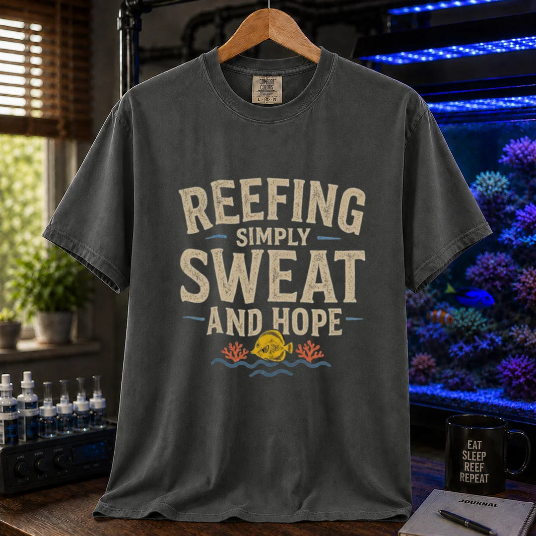 Saltwater aquarium graphic t-shirt featuring distressed cream typography reading Reefing: Simply Sweat And Hope with a yellow tang and coral illustration printed on a dark grey tee displayed in a reef room setting