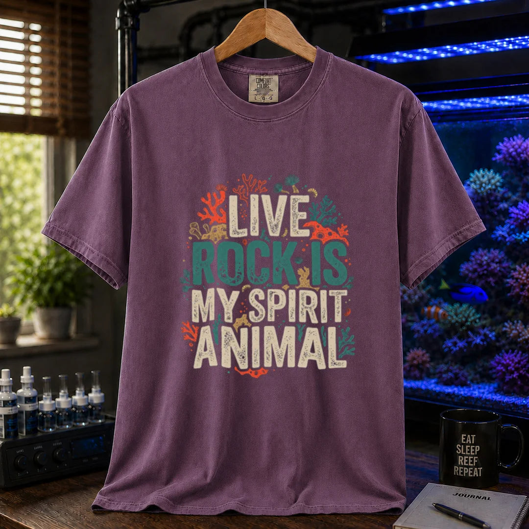 Saltwater aquarium graphic t-shirt featuring distressed cream and turquoise typography reading Live Rock Is My Spirit Animal framed by colorful coral illustrations printed on a purple tee displayed in a reef room setting