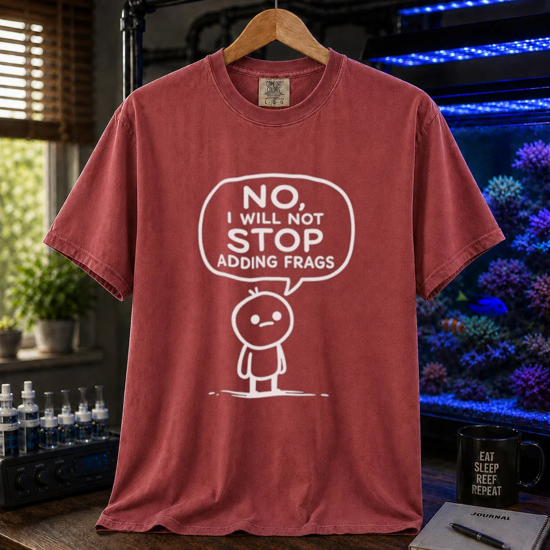 Saltwater aquarium graphic t-shirt featuring a white line-art cartoon character and speech bubble reading No, I Will Not Stop Adding Frags printed on a maroon, red tee displayed in a reef room setting