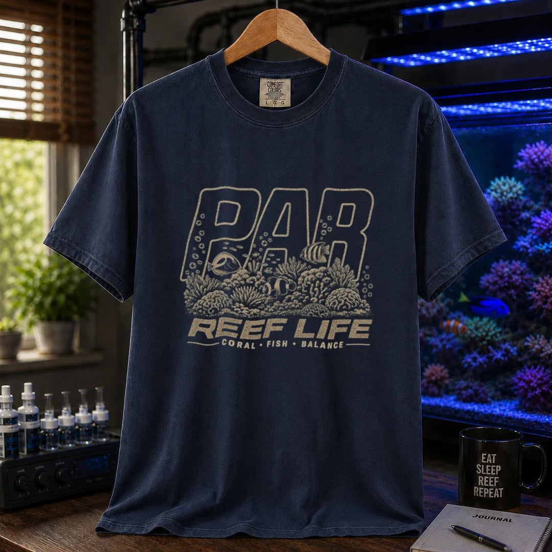 Saltwater aquarium graphic t-shirt featuring distressed cream typography reading PAR and Reef Life with an intricate engraved reef, coral, and fish illustration printed on a navy tee displayed in a reef room setting