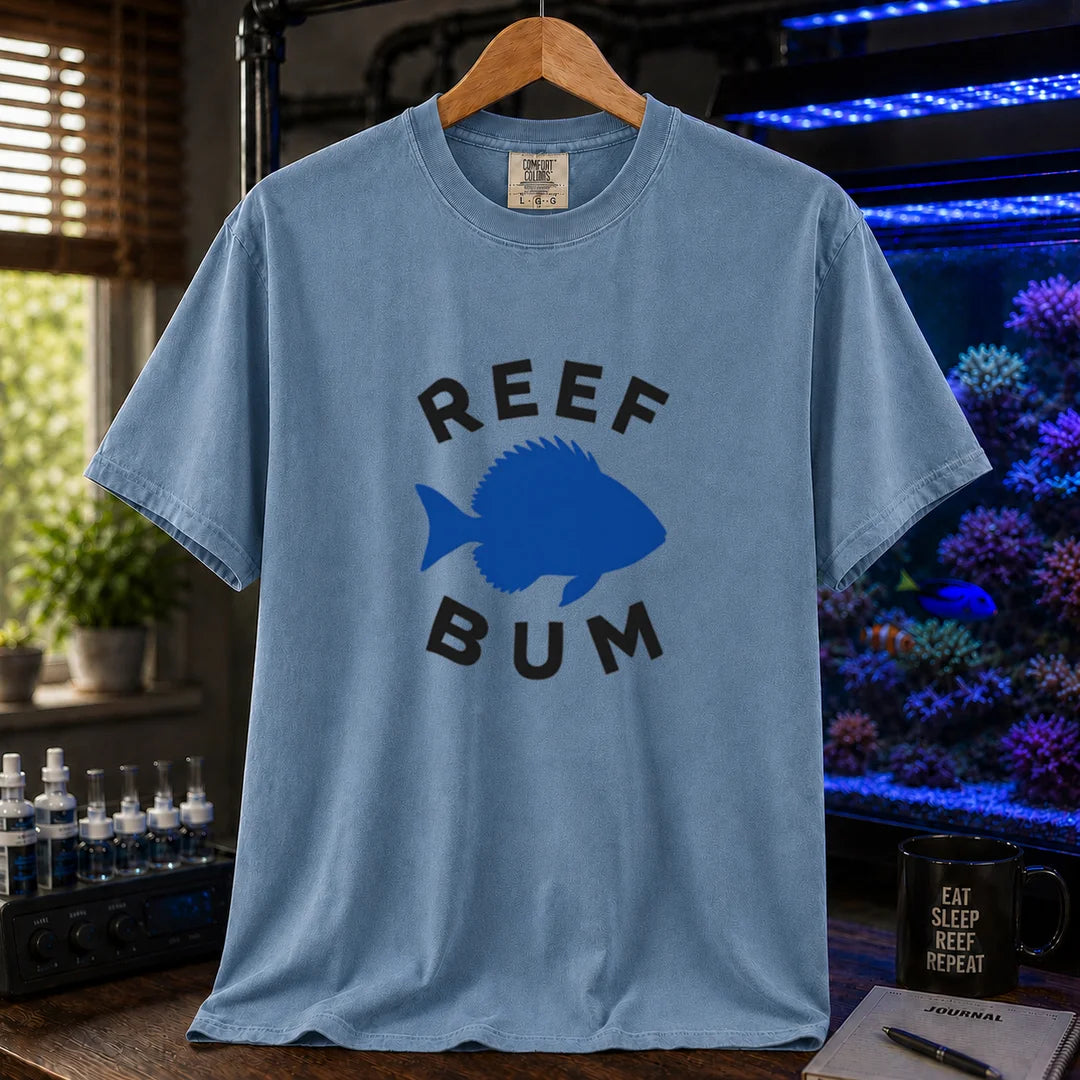 Saltwater aquarium graphic t-shirt featuring bold black typography reading Reef Bum arched around a solid blue silhouette of a fish on a blue background