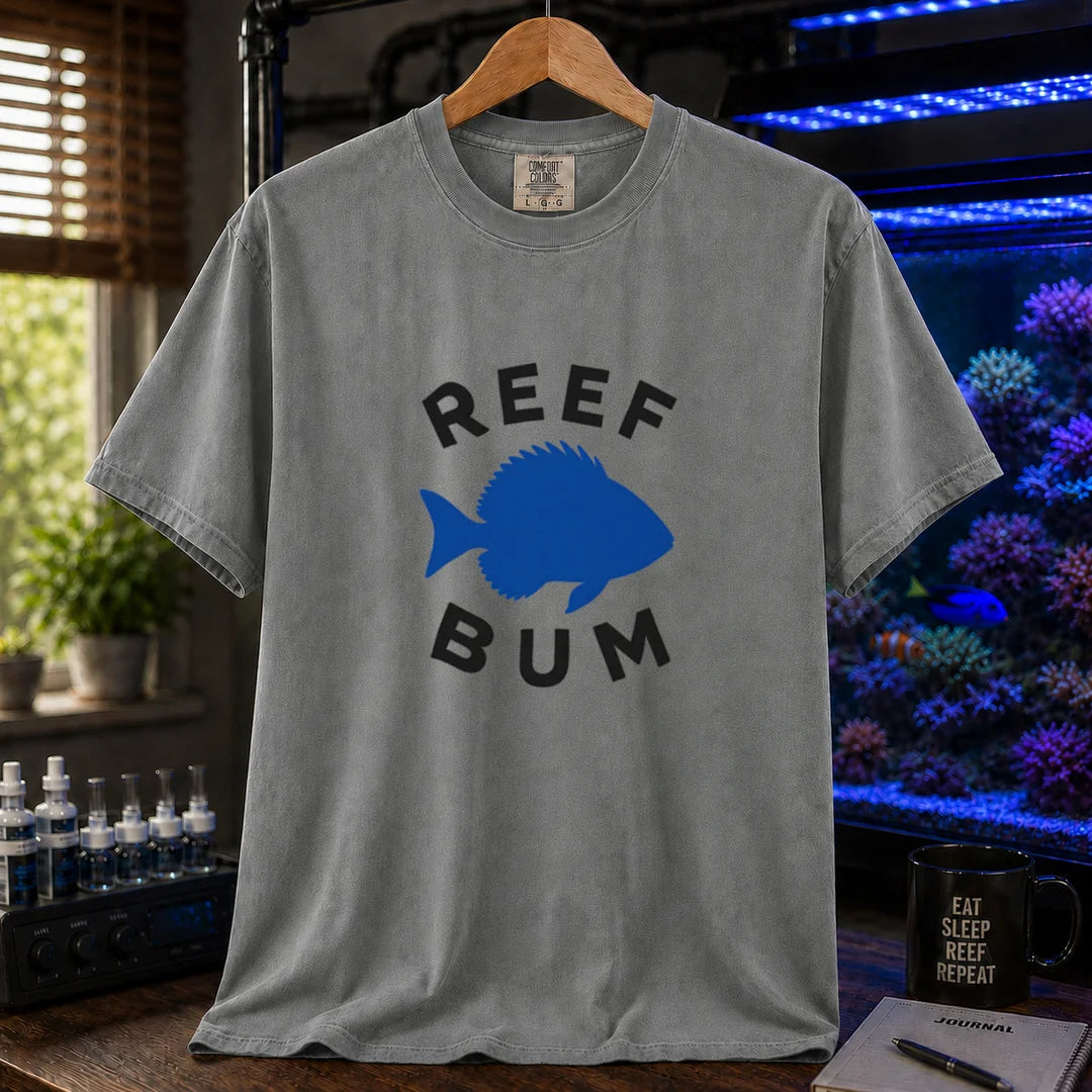 Saltwater aquarium graphic t-shirt featuring bold black typography reading Reef Bum arched around a solid blue silhouette of a fish on a grey background