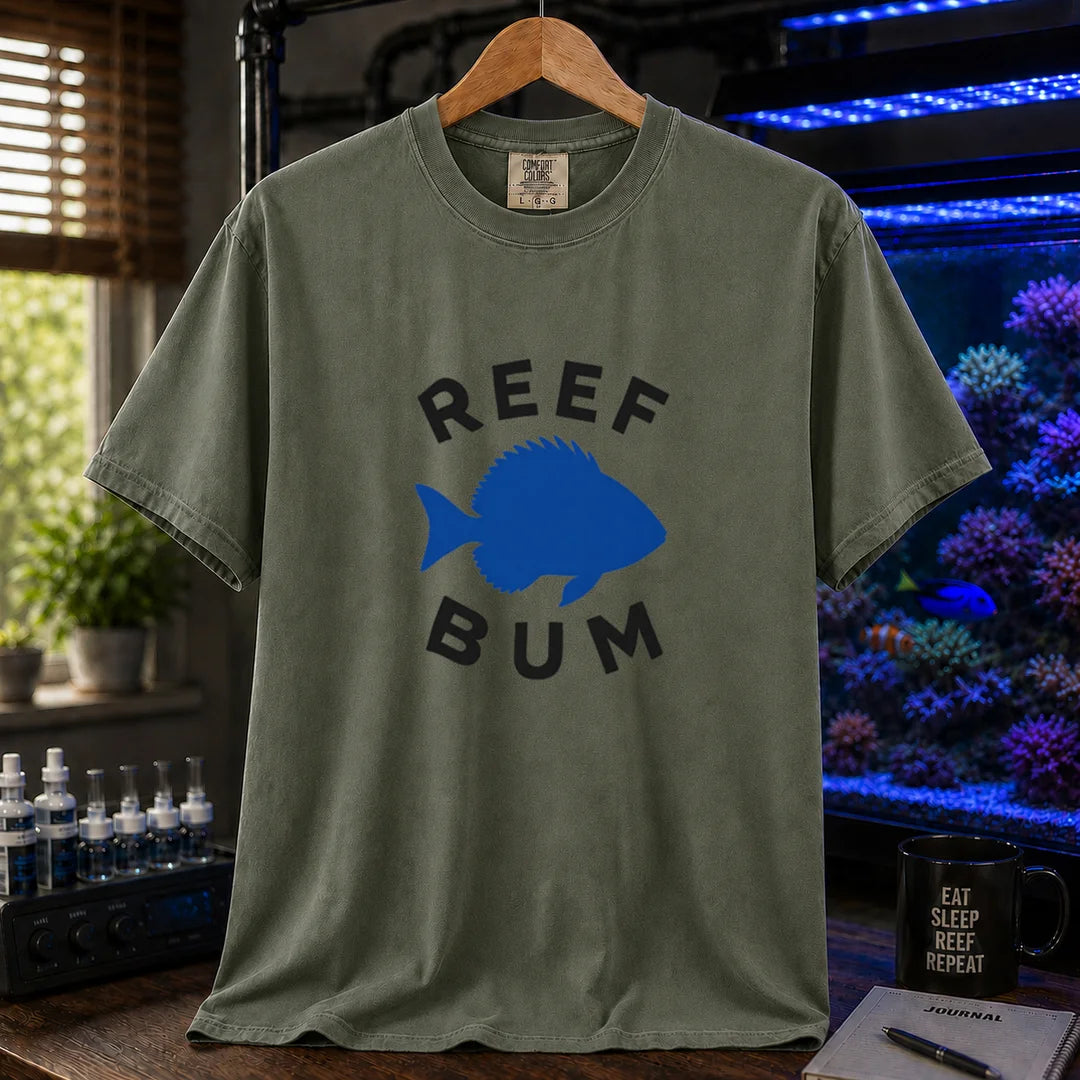 Saltwater aquarium graphic t-shirt featuring bold black typography reading Reef Bum arched around a solid blue silhouette of a fish on a military green background