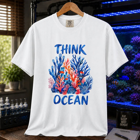 Saltwater aquarium graphic t-shirt featuring blue hand-lettered typography reading Think Ocean framing a vibrant watercolor illustration of blue and orange coral reefs on a white shirt