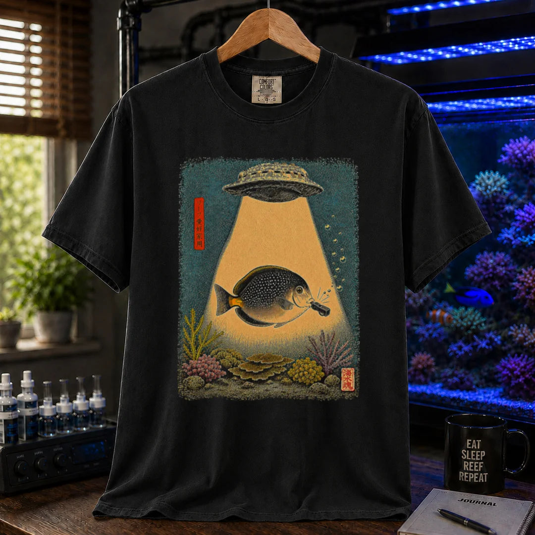 Saltwater aquarium graphic t-shirt featuring a vintage woodblock print style UFO abducting a reef fish with a tractor beam over coral on a black shirt