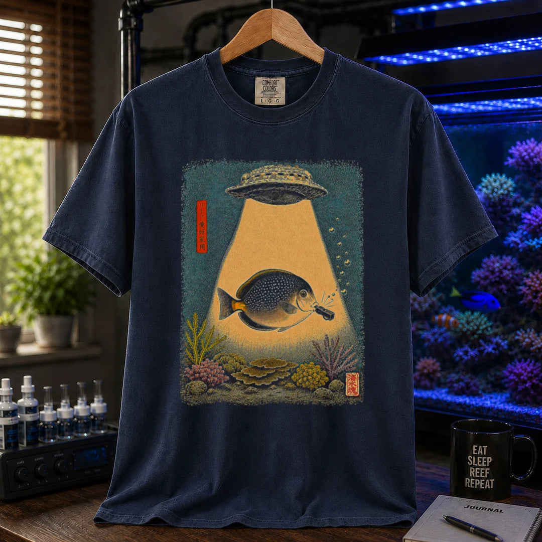 Saltwater aquarium graphic t-shirt featuring a vintage woodblock print style UFO abducting a reef fish with a tractor beam over coral on a navy shirt