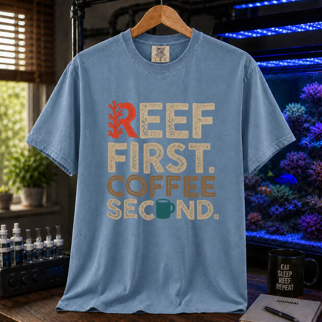 Saltwater aquarium graphic t-shirt featuring distressed typography reading Reef First Coffee Second with a red coral graphic and teal coffee mug icon on a blue shirt