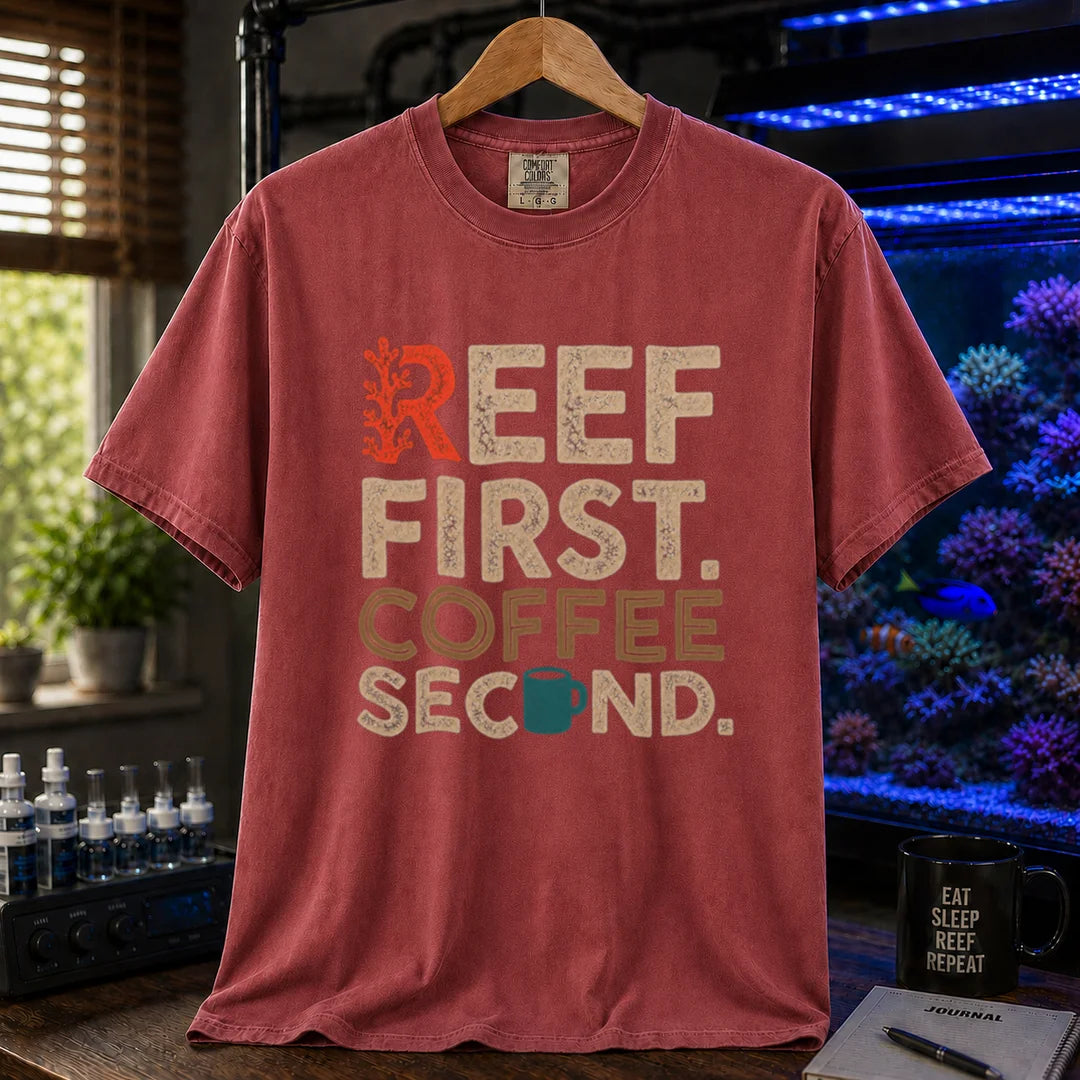 Saltwater aquarium graphic t-shirt featuring distressed typography reading Reef First Coffee Second with a red coral graphic and teal coffee mug icon on a maroon, red shirt