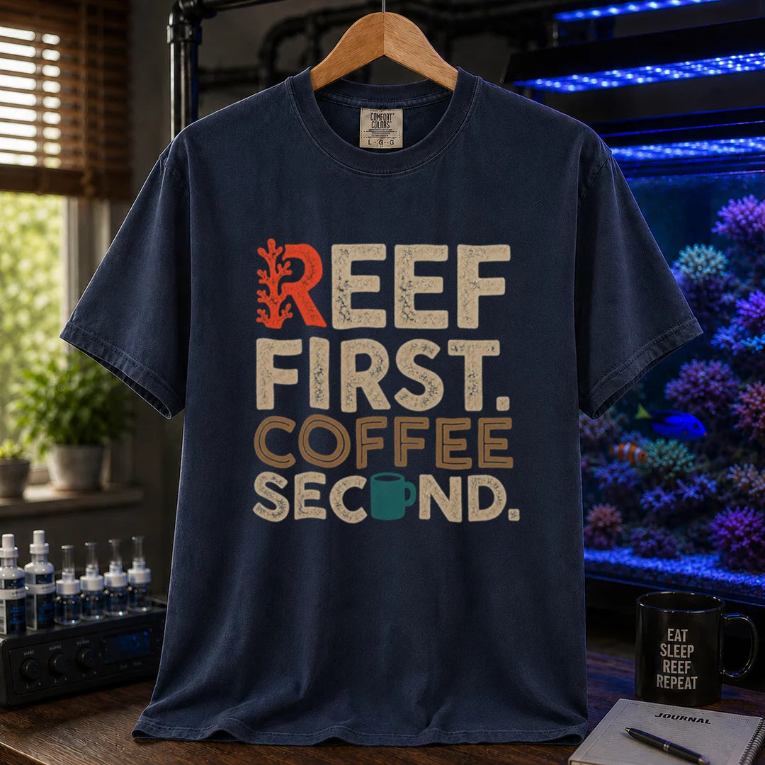 Saltwater aquarium graphic t-shirt featuring distressed typography reading Reef First Coffee Second with a red coral graphic and teal coffee mug icon on a navy shirt