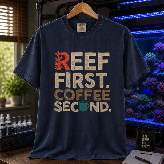Saltwater aquarium graphic t-shirt featuring distressed typography reading Reef First Coffee Second with a red coral graphic and teal coffee mug icon on a navy shirt