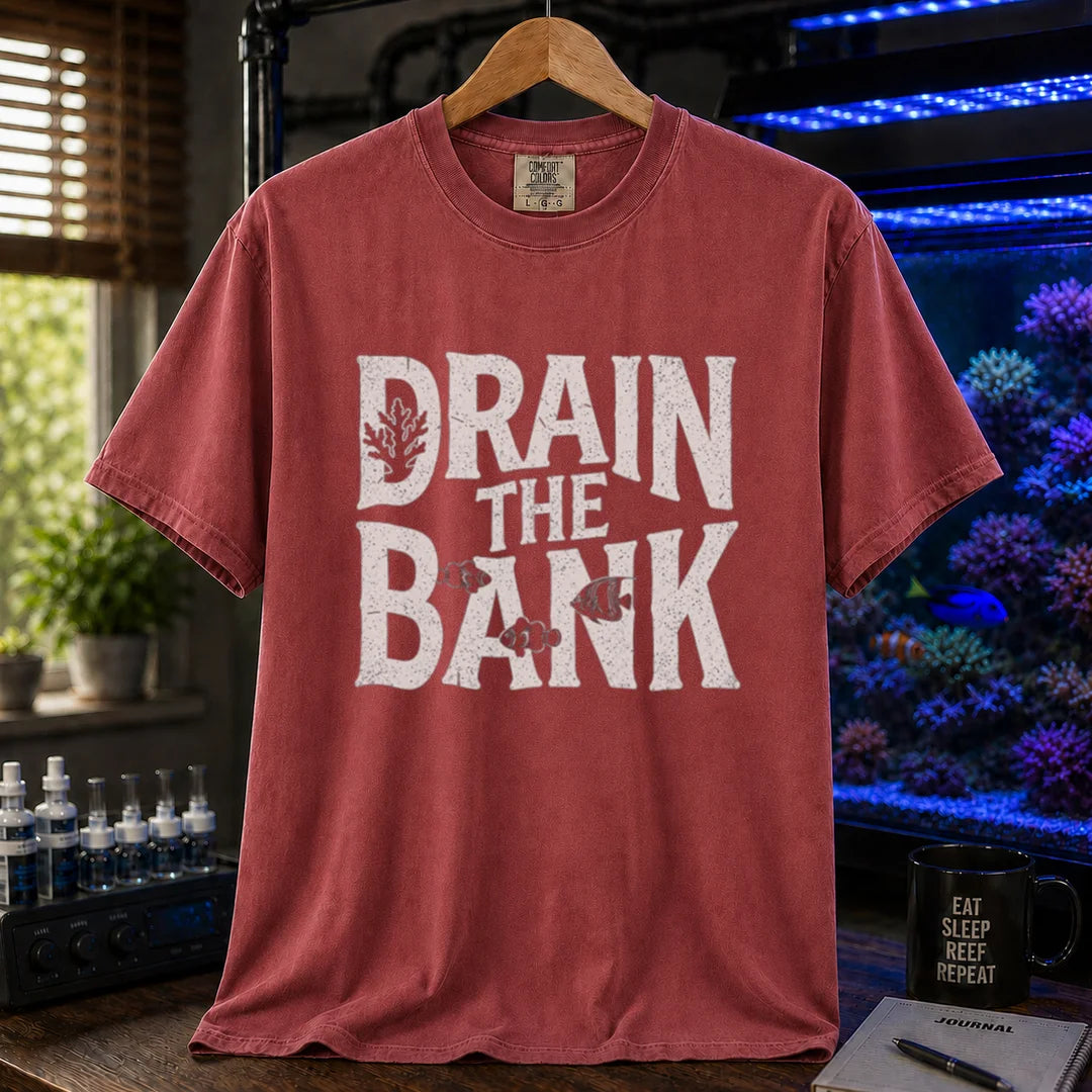 Saltwater aquarium graphic t-shirt featuring distressed white block lettering reading Drain The Bank with subtle fish and coral shapes on a maroon, red shirt