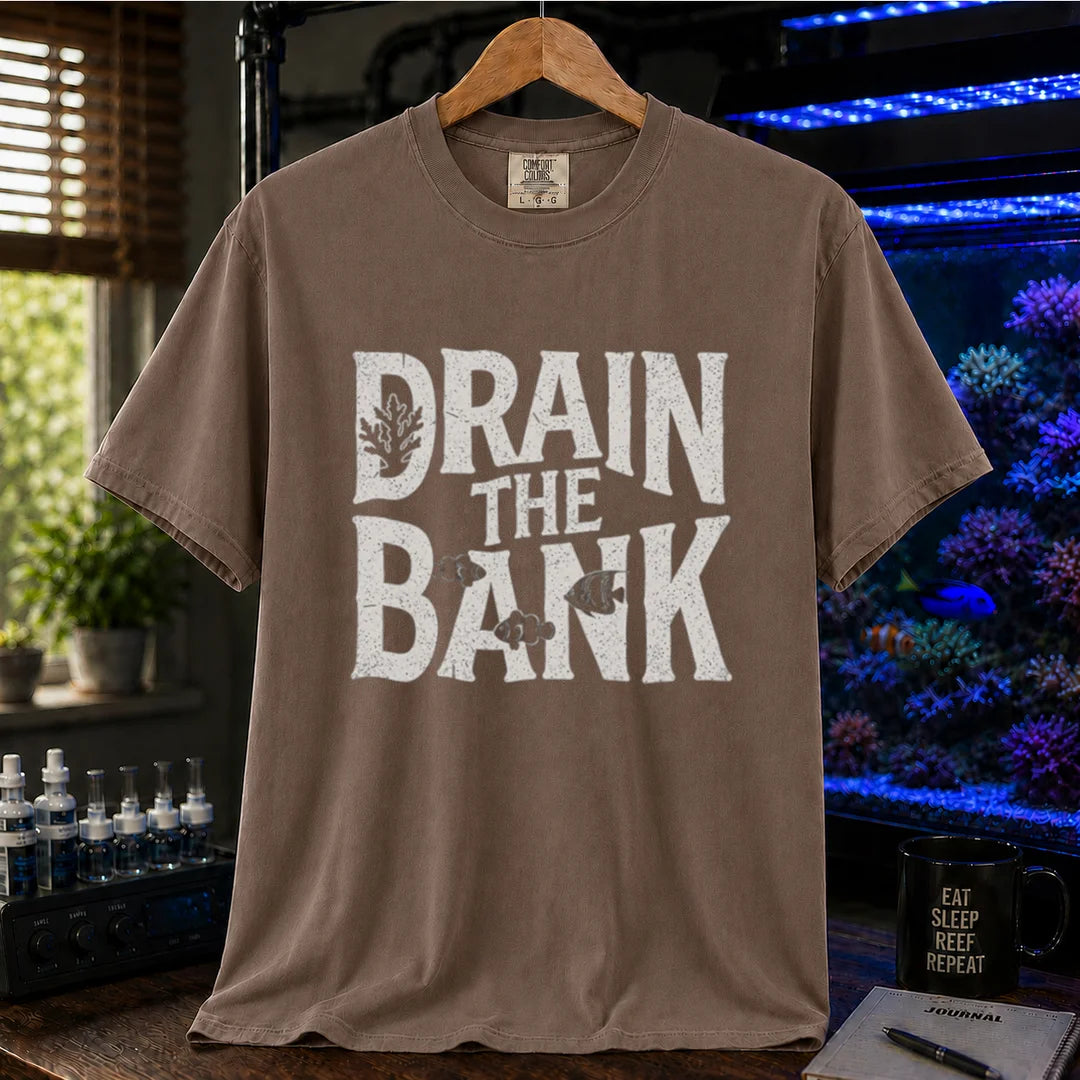 Saltwater aquarium graphic t-shirt featuring distressed white block lettering reading Drain The Bank with subtle fish and coral shapes on a brown shirt