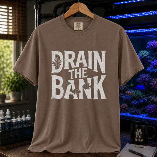 Saltwater aquarium graphic t-shirt featuring distressed white block lettering reading Drain The Bank with subtle fish and coral shapes on a brown shirt
