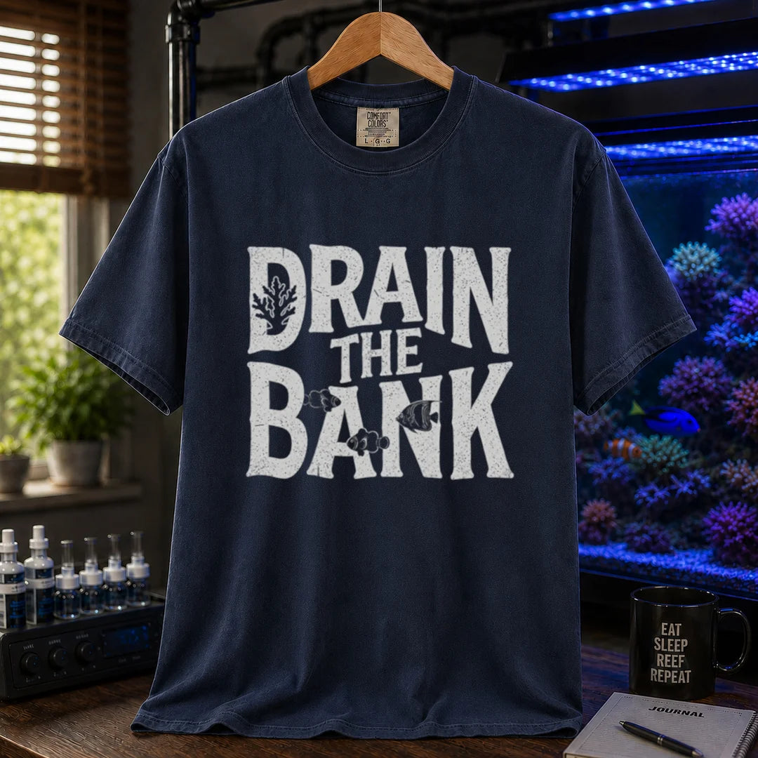 Saltwater aquarium graphic t-shirt featuring distressed white block lettering reading Drain The Bank with subtle fish and coral shapes on a navy shirt