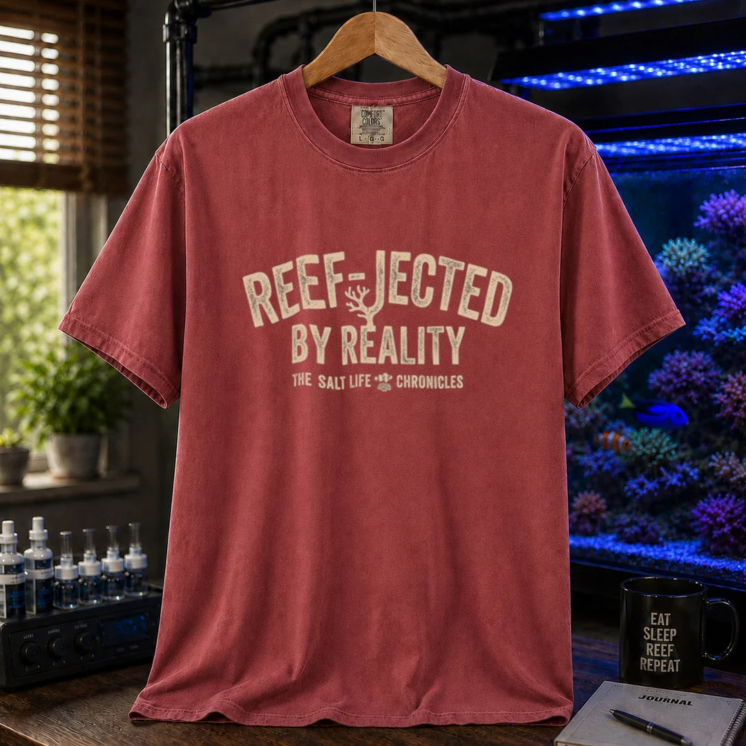 Saltwater aquarium graphic t-shirt featuring distressed typography reading Reef-Jected By Reality The Salt Life Chronicles on a maroon, red shirt