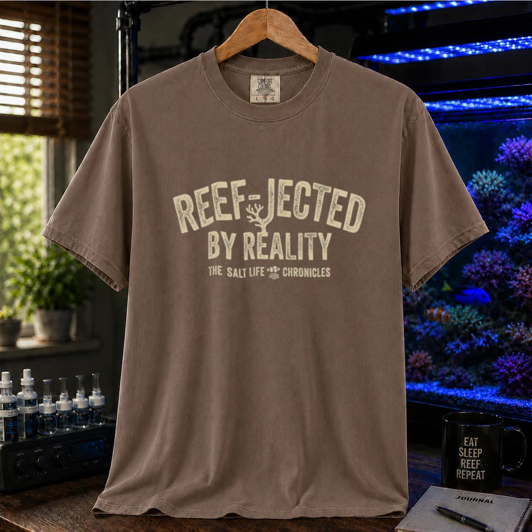 Saltwater aquarium graphic t-shirt featuring distressed typography reading Reef-Jected By Reality The Salt Life Chronicles on a brown shirt