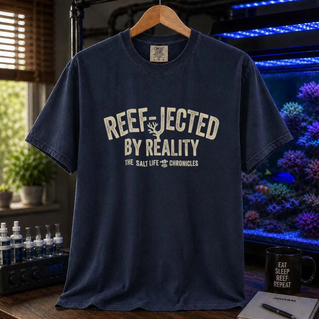 Saltwater aquarium graphic t-shirt featuring distressed typography reading Reef-Jected By Reality The Salt Life Chronicles on a navy shirt