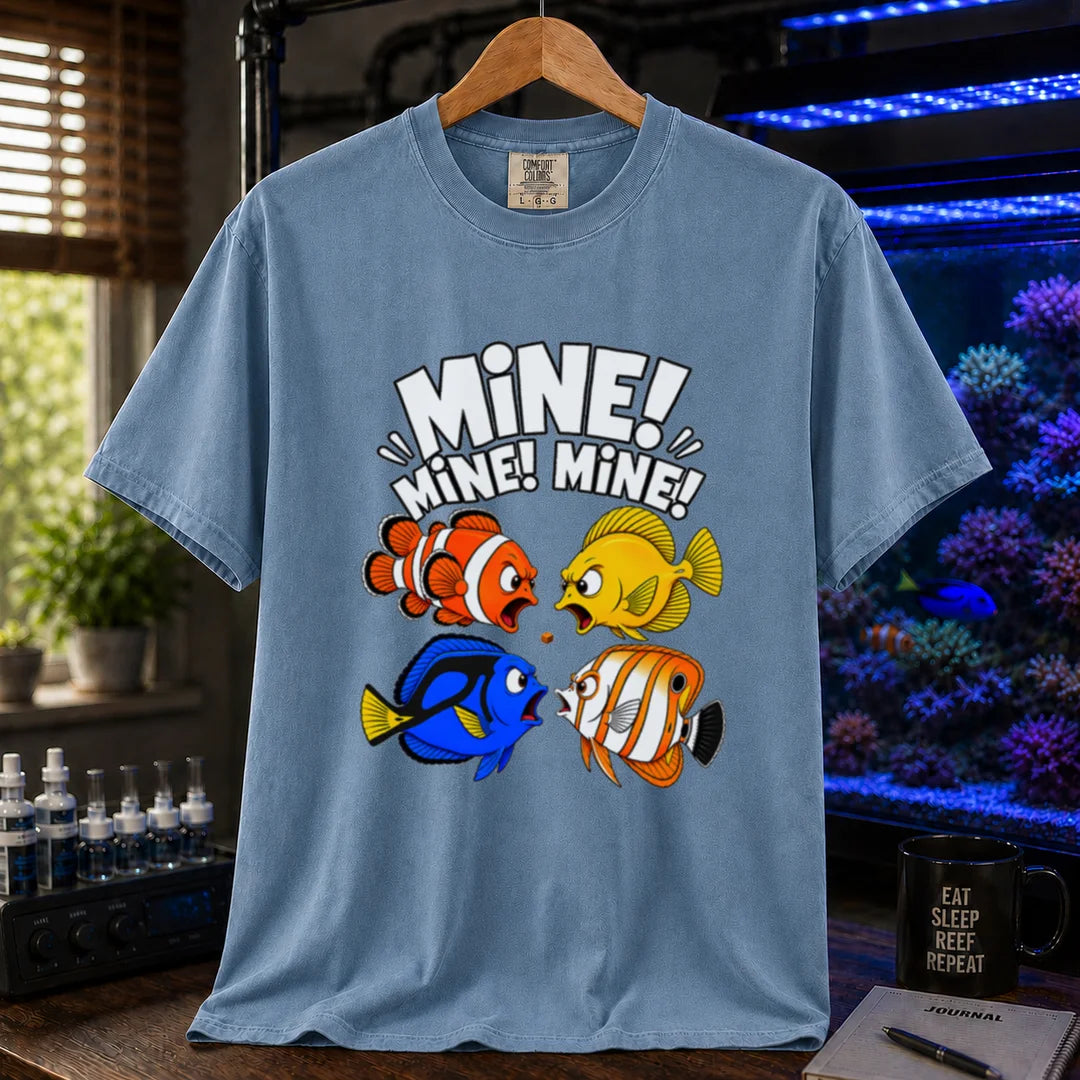 Saltwater aquarium graphic t-shirt featuring text reading Mine Mine Mine above four colorful reef fish fighting over a single piece of food on a blue shirt