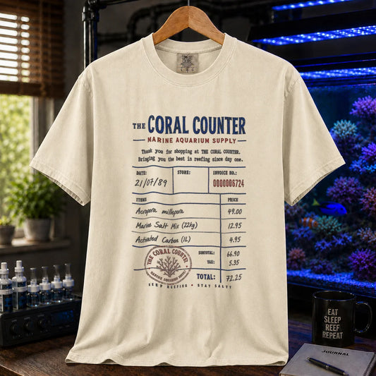 Saltwater aquarium graphic t-shirt featuring a vintage store receipt design listing coral, salt mix, and carbon with a stamp reading The Coral Counter on a beige, cream, ivory shirt