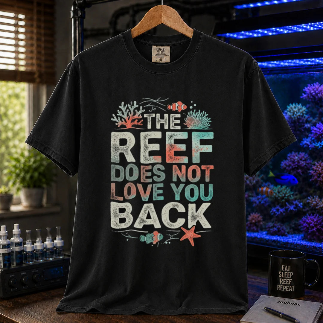 Saltwater aquarium graphic t-shirt featuring distressed multi-row typography reading The Reef Does Not Love You Back with coral and clownfish illustrations on a black shirt