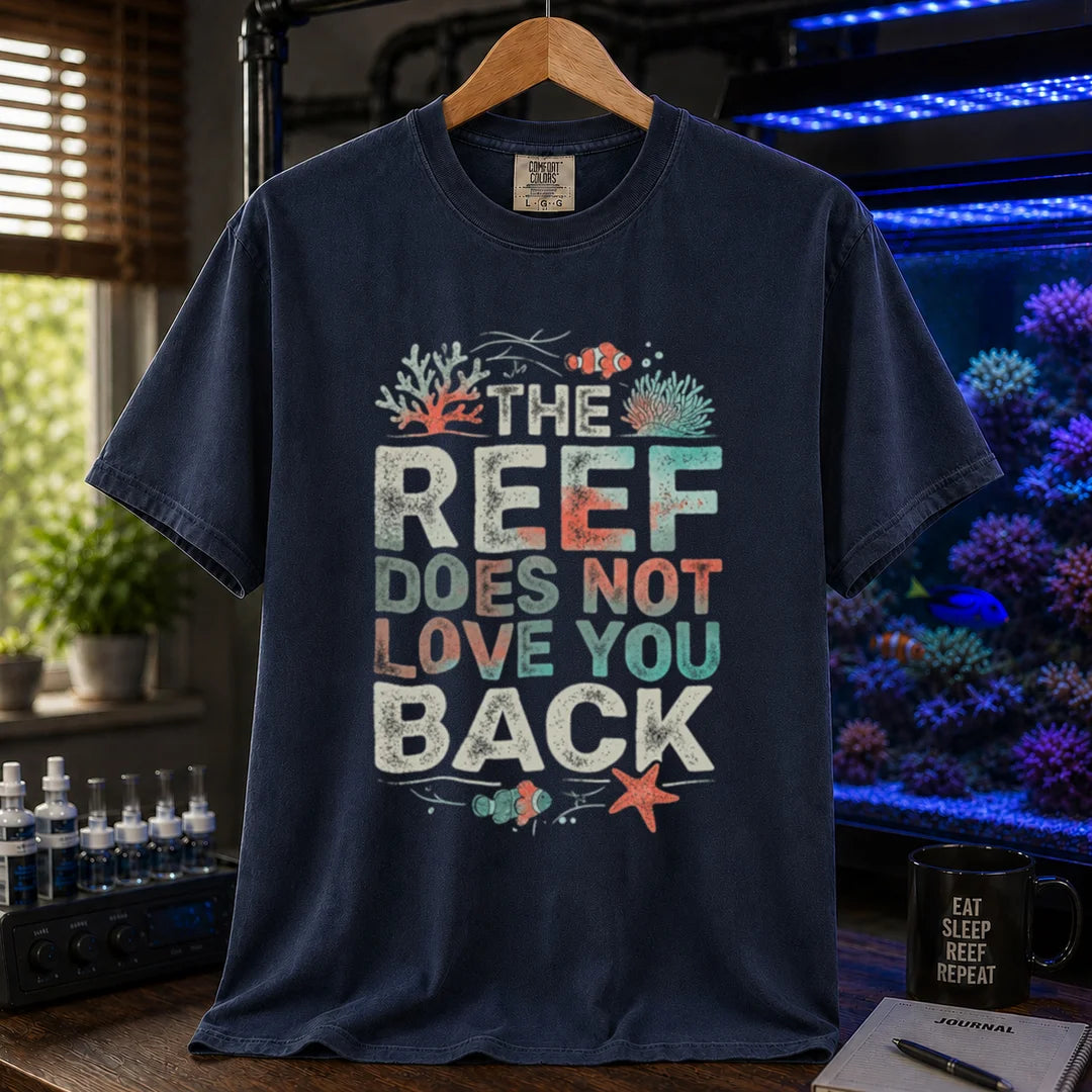 Saltwater aquarium graphic t-shirt featuring distressed multi-row typography reading The Reef Does Not Love You Back with coral and clownfish illustrations on a navy shirt
