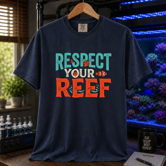 Saltwater aquarium graphic t-shirt featuring distressed multi-row typography reading Respect Your Reef in turquoise, cream, and orange with coral and clownfish accents on a navy shirt