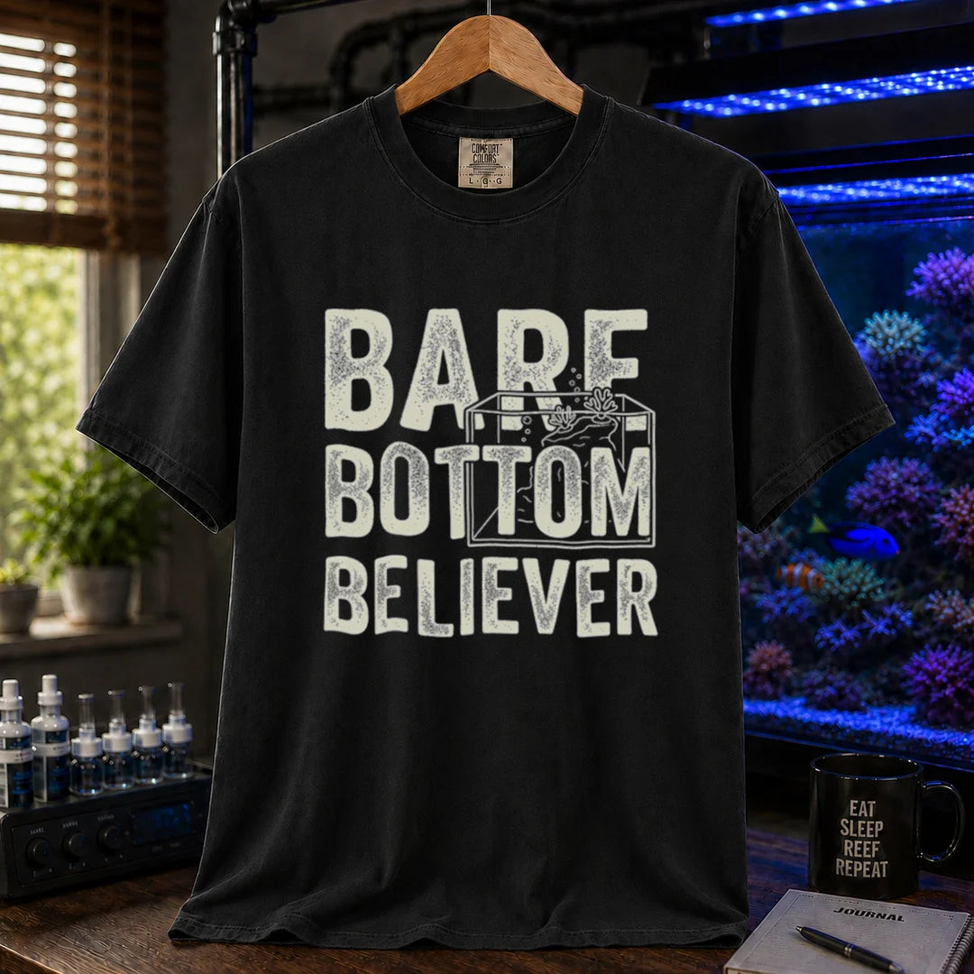 Saltwater aquarium graphic t-shirt featuring distressed typography reading Bare Bottom Believer with an aquarium outline illustration on a black shirt