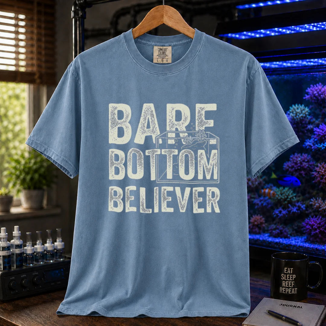 Saltwater aquarium graphic t-shirt featuring distressed typography reading Bare Bottom Believer with an aquarium outline illustration on a blue shirt