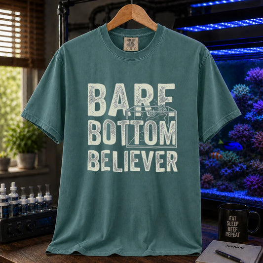 Saltwater aquarium graphic t-shirt featuring distressed typography reading Bare Bottom Believer with an aquarium outline illustration on a green shirt