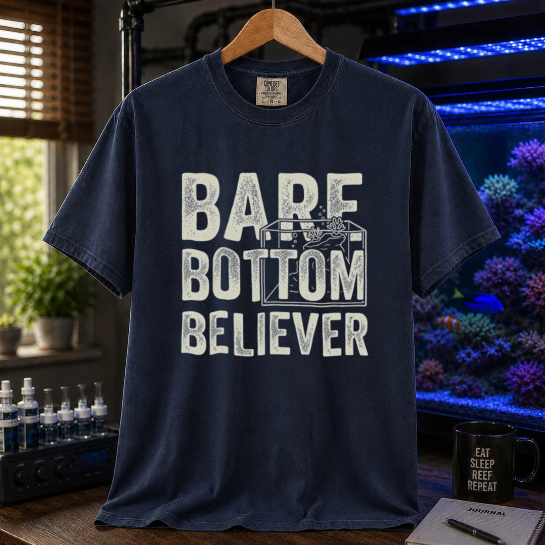 Saltwater aquarium graphic t-shirt featuring distressed typography reading Bare Bottom Believer with an aquarium outline illustration on a navy shirt
