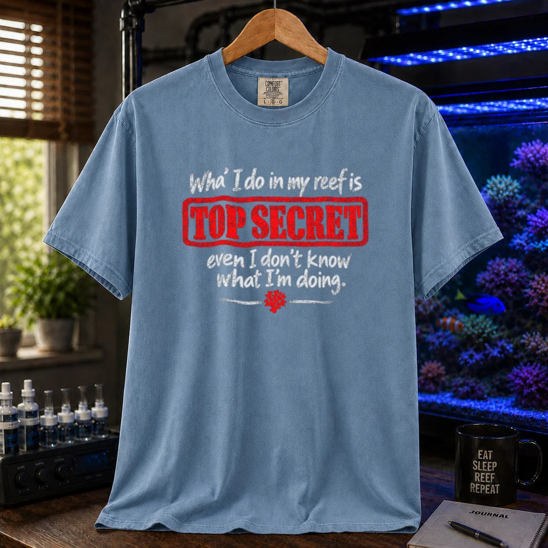 Saltwater aquarium graphic t-shirt featuring distressed typography reading What I do in my reef is Top Secret even I don't know what I'm doing with a red stamp effect on a blue shirt