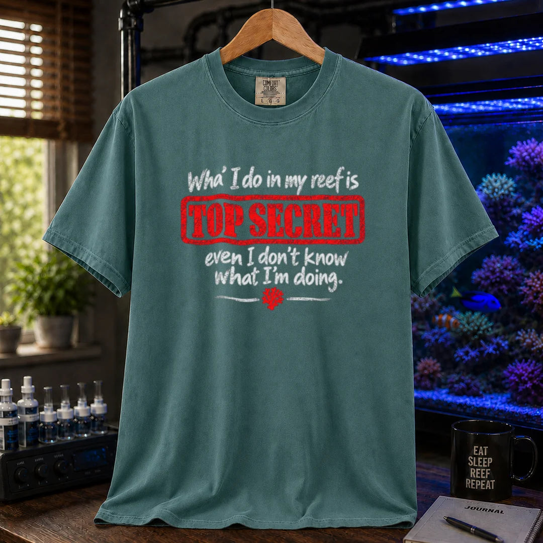 Saltwater aquarium graphic t-shirt featuring distressed typography reading What I do in my reef is Top Secret even I don't know what I'm doing with a red stamp effect on a green shirt