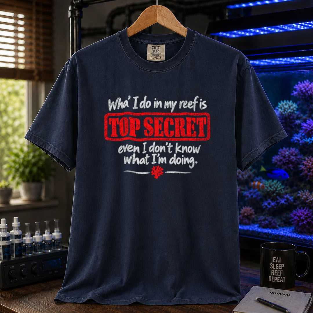 Saltwater aquarium graphic t-shirt featuring distressed typography reading What I do in my reef is Top Secret even I don't know what I'm doing with a red stamp effect on a navy shirt