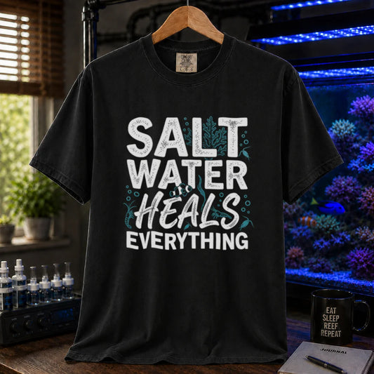 Saltwater aquarium graphic t-shirt featuring distressed typography reading Salt Water Heals Everything with small coral and fish illustrations on a black shirt