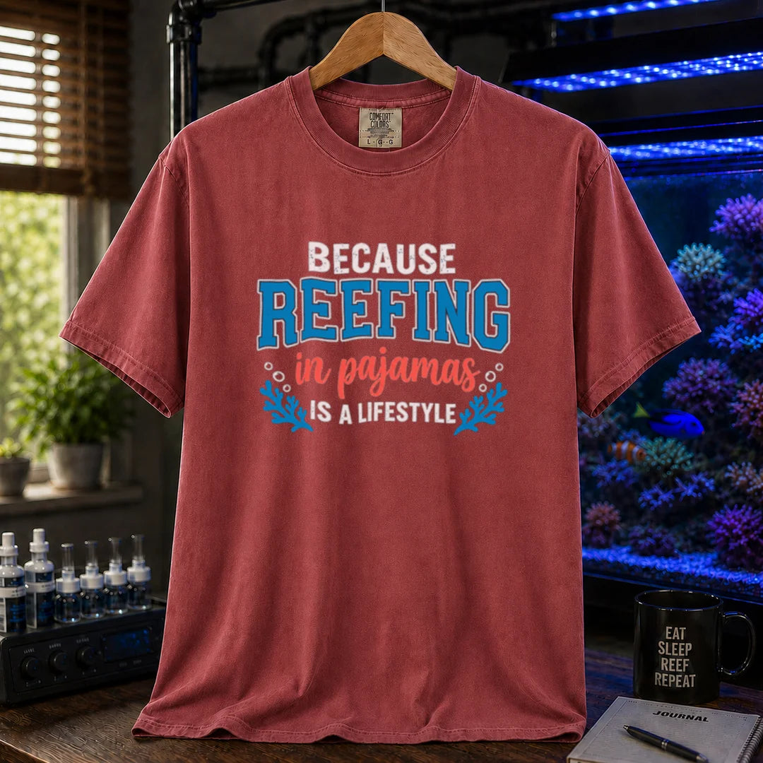 Saltwater aquarium graphic t-shirt featuring distressed typography reading Because Reefing In Pajamas Is A Lifestyle with blue coral and bubble illustrations on a maroon, red shirt