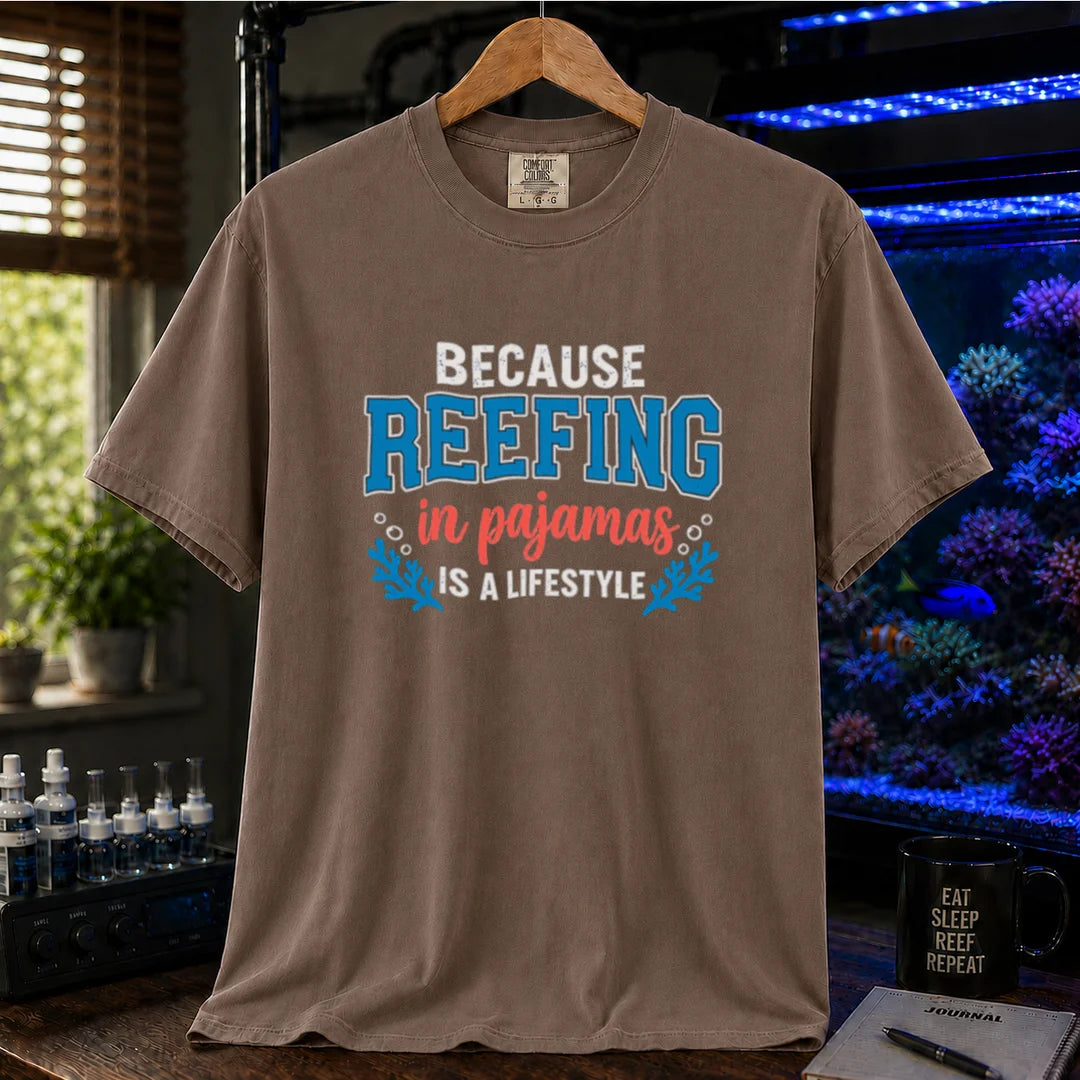 Saltwater aquarium graphic t-shirt featuring distressed typography reading Because Reefing In Pajamas Is A Lifestyle with blue coral and bubble illustrations on a brown shirt